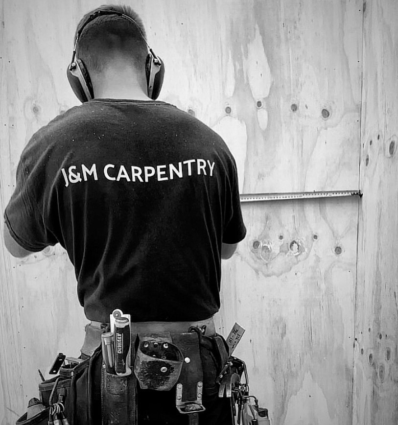 A J&M Carpentry team member at work wearing the company’s branded shirt
